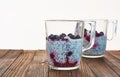 Useful and nourishing breakfast, pudding of currant berries, cherries with yoghurt and chia seeds in glass cups on wooden backgrou