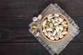 Useful nuts - pistachios in a ceramic bowl on a dark wooden background.