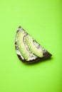 Useful sandwiches with avocado, cheese, sesame and black bread on a bright green background, vertically