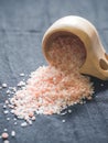 Useful spices concept. Large dark pink himalayan salt spilled from a wooden cup onto a black tablecloth. Closeup Royalty Free Stock Photo
