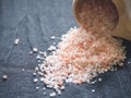 Useful spices concept. Large dark pink himalayan salt spilled from a wooden cup onto a black tablecloth. Closeup Royalty Free Stock Photo