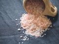 Useful spices concept. Large dark pink himalayan salt spilled from a wooden cup onto a black tablecloth. Closeup Royalty Free Stock Photo