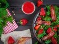 Useful strawberry salad with arugula, nuts and bacon, berry sauce