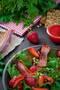 Useful strawberry salad with arugula, nuts and bacon, berry sauce