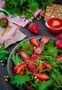 Useful strawberry salad with arugula, nuts and bacon, berry sauce