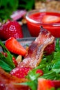 Useful strawberry salad with arugula, nuts and bacon, berry sauce