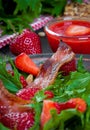 Useful strawberry salad with arugula, nuts and bacon, berry sauce