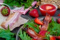 Useful strawberry salad with arugula, nuts and bacon, berry sauce