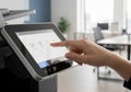 Hand interacting with modern printer touchscreen interface in a bright office environment, showcasing printing options and user Royalty Free Stock Photo