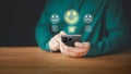 User hand using a mobile phone with pop up smile face icon for feedback review satisfaction service opinion and testimonial.