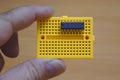 A user holding a yellow protoboard horizontally with an ic mounted