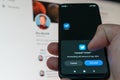 User uninstalling social media Twitter from a Iohone smartphone against the backdrop of the monitor with an open profile of Elon M