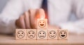 Users choose the highest satisfaction. Businessman's hand selects a smiley face on a wooden block. 5 star satisfaction.