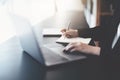 usiness woman writing marketing plan in notebook ready to use computer in office