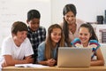 Using all the resources the internet has to offer. Shot of a group of schoolchildren using a laptop in class with their Royalty Free Stock Photo