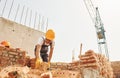 Using bricks. Young construction worker in uniform is busy at the unfinished building Royalty Free Stock Photo
