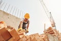 Using bricks. Young construction worker in uniform is busy at the unfinished building Royalty Free Stock Photo