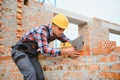 Using bricks. Young construction worker in uniform is busy at the unfinished building Royalty Free Stock Photo