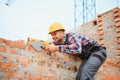 Using bricks. Young construction worker in uniform is busy at the unfinished building Royalty Free Stock Photo