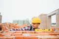Using bricks. Young construction worker in uniform is busy at the unfinished building Royalty Free Stock Photo