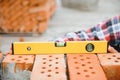 Using bricks. Young construction worker in uniform is busy at the unfinished building Royalty Free Stock Photo