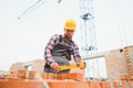 Using bricks. Young construction worker in uniform is busy at the unfinished building Royalty Free Stock Photo