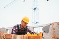 Using bricks. Young construction worker in uniform is busy at the unfinished building Royalty Free Stock Photo