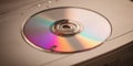 Using a CD in a computer disk drive to access data and music from the optical disc on a work desk Royalty Free Stock Photo