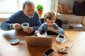 Grandfather and his grandson spending time insulated at home, stadying, watching cinema, shopping together