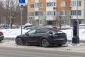 Using the electric car in freezing temperatures. Tesla Model 3 electric car charging in a street parking lot in winter