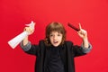 Portrait of liitle boy, kid in image of stylish hairdresser, barber isolated on red studio background. Concept of