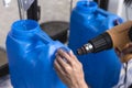 Using a heat gun to tighten the plastic seal on the cap lid of a blue 20 liter HPDE water container. A purified water refilling Royalty Free Stock Photo