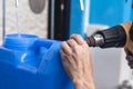 Using a heat gun to tighten the plastic seal on the cap lid of a blue 20 liter HPDE water container. A purified water refilling Royalty Free Stock Photo