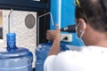 Using a heat gun to tighten the plastic seal on the cap lid of a clear HPDE water container. A purified water refilling station Royalty Free Stock Photo