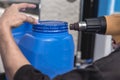 Using a heat gun to tighten the plastic seal on the lid of a blue 20 liter HPDE water container. A purified water refilling Royalty Free Stock Photo