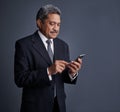 Using his smart device to make smart connections. Studio shot of a mature businessman using his cellphone. Royalty Free Stock Photo
