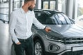 Using the keys remote controller. Young man in white clothes is in the car dealership Royalty Free Stock Photo