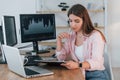 Using laptop. Female stock broker in casual clothes is working in the office by pc