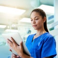 Using the latest technology to her patients benefit. a young nurse using a tablet while standing inside a clinic. Royalty Free Stock Photo