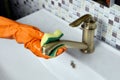 Using latex gloves when wiping brass faucet with cleaning sponge.