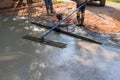 By using a long trowel a cement concrete leveling tool, the masonry worker plastered the leveling cement concrete patio