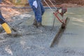 Using a machine, the compacted layer of fresh concrete is aligned on the new driveway construction. Royalty Free Stock Photo