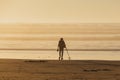 Using a metal detector to search for hidden treasure on a beach at sunset Royalty Free Stock Photo