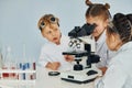 Using microscope. Children in white coats plays a scientists in lab by using equipment Royalty Free Stock Photo