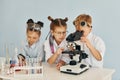 Using microscope. Children in white coats plays a scientists in lab by using equipment Royalty Free Stock Photo