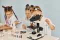 Using microscope. Children in white coats plays a scientists in lab by using equipment Royalty Free Stock Photo