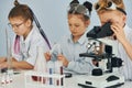 Using microscope. Children in white coats plays a scientists in lab by using equipment Royalty Free Stock Photo