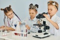 Using microscope. Children in white coats plays a scientists in lab by using equipment Royalty Free Stock Photo