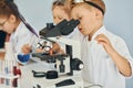 Using microscope. Children in white coats plays a scientists in lab by using equipment Royalty Free Stock Photo