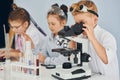 Using microscope. Children in white coats plays a scientists in lab by using equipment Royalty Free Stock Photo